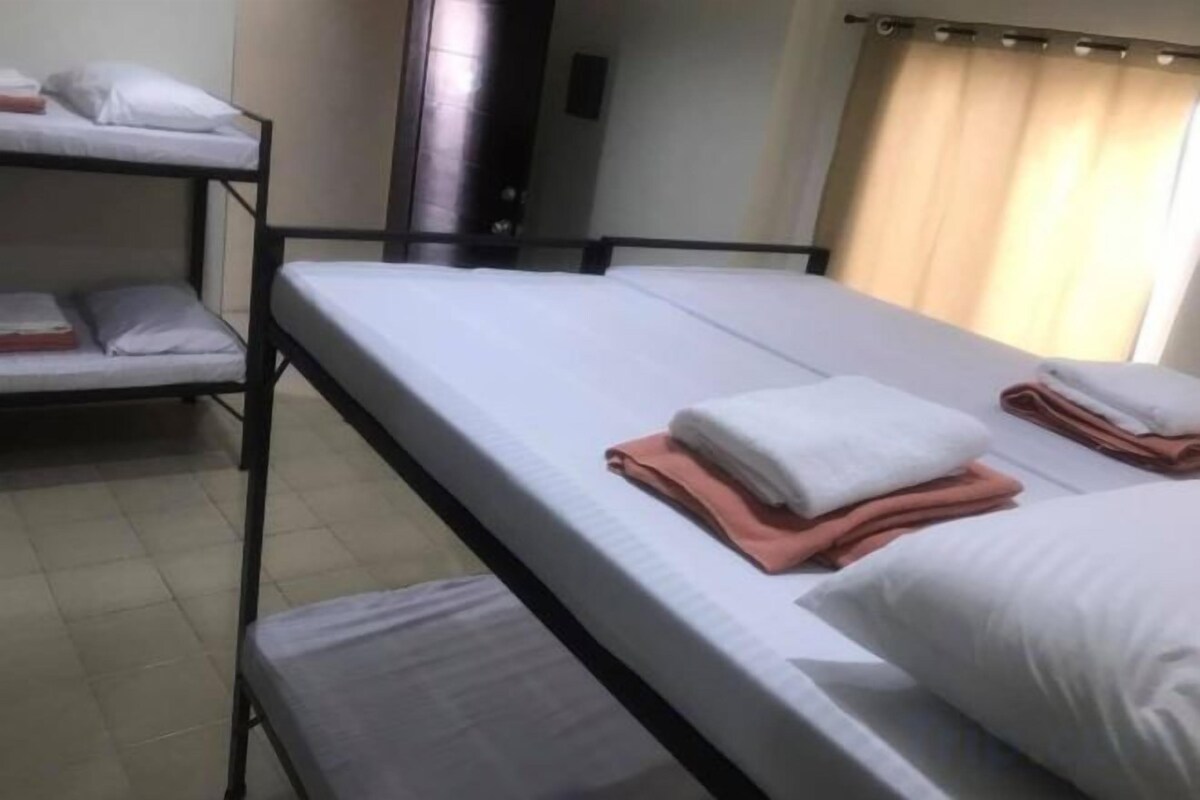A room with bunk beds, a bed, and a window with curtains.