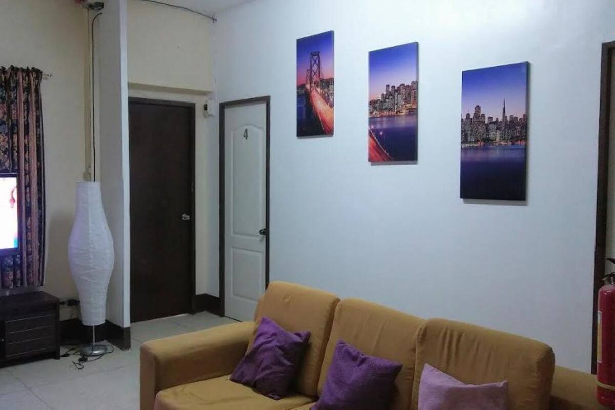 Ein Wohnzimmer mit Fernseher, einer Couch und drei gerahmten Bildern an der Wand.