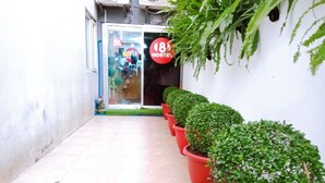 A hallway with potted plants, a sign for '18 Hostel', and a glass door entrance. - 8 Hostel at Quiapo (Manila)