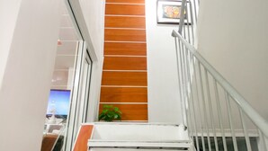 A staircase with white railings and wooden steps leading to a lower level. - 8 Hostel at Quiapo (Manila)