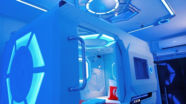 A futuristic room with a circular light fixture, a bed with a red and white pillow, and a control panel on the wall. - 8 Hostel at Quiapo (Manila)