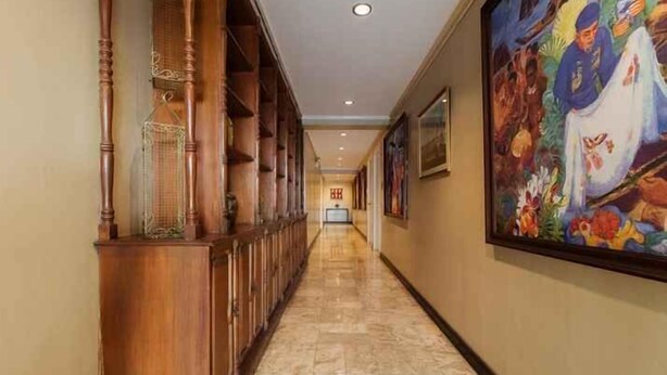 A hallway with wooden paneling, a tiled floor, and a large painting on the wall. - Rd Suites Greenbelt (Makati)