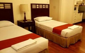 A hotel room with two beds, a nightstand, a lamp, and a microwave. - Rd Suites Greenbelt (Makati)