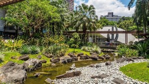 A garden with a pond, rocks, and palm trees. - Rd Suites Greenbelt (Makati)
