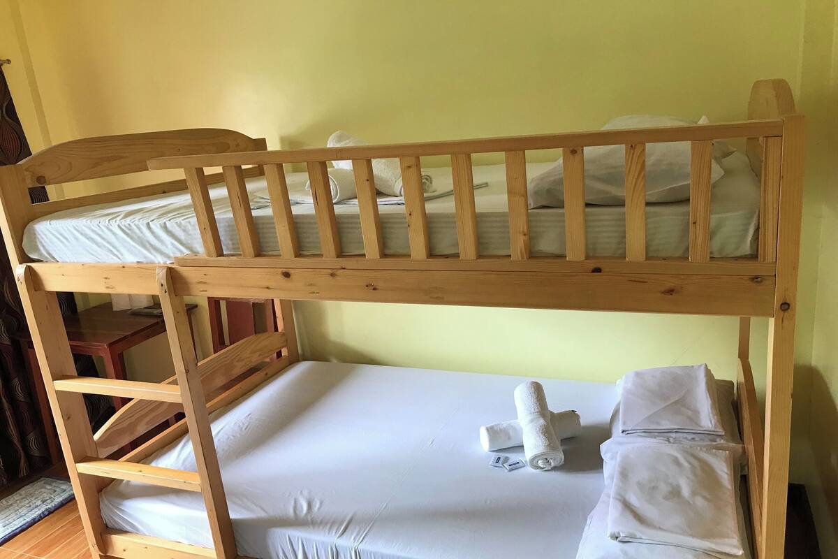 A bunk bed with a wooden frame and white bedding.