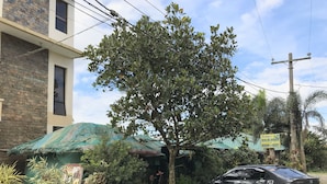 A building with a green roof, a parked car, and a sign for "Junta's Bulalohan Room for Rent". - Jhunlyn Rooms for Rent Tagaytay (Tagaytay)