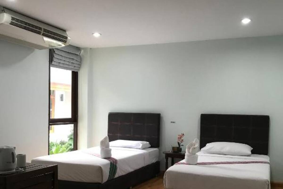 A hotel room with two beds, a dresser, and an air conditioning unit.