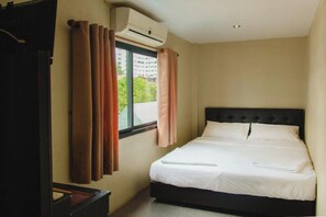 A hotel room with a bed, curtains, an air conditioning unit, and a window. - G.I Lodge by Zuzu (Pattaya)
