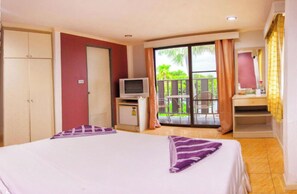 A hotel room with a bed, a television, a small desk, and a balcony with outdoor furniture. - G.I Lodge by Zuzu (Pattaya)