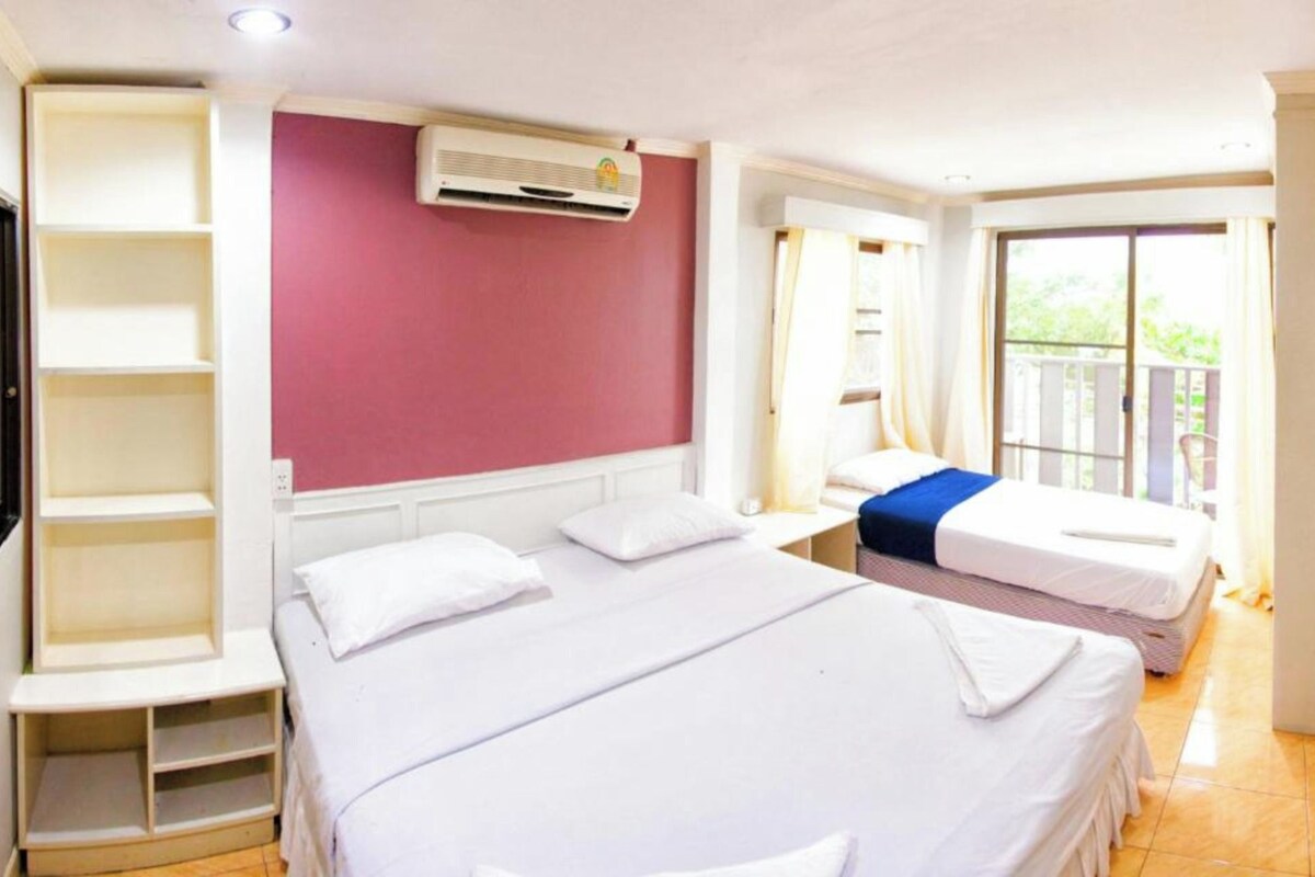 A hotel room with a large bed, a built-in wardrobe, an air conditioning unit, and a balcony with a view.