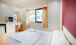 A hotel room with a bed, a desk, a chair, a television, and a window with curtains. - G.I Lodge by Zuzu (Pattaya)