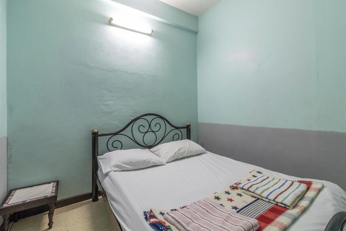 A single bed with a metal headboard in a room with light blue walls and a gray lower half.