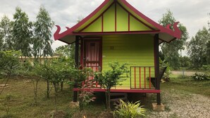 Un pequeño edificio de una sola planta con fachada verde y roja, número 18, rodeado de vegetación.