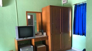 A room with a wooden desk, a television, a wardrobe, and a small refrigerator. - Romsai Resort (Bang Lamung)