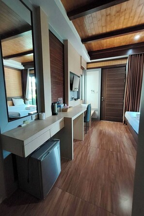 Habitación de hotel moderna con techo de madera, un espejo grande, un escritorio con silla, cama y armario.