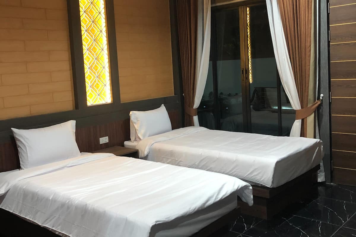 A hotel room with two beds, a large window with curtains, and a wooden ceiling.