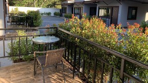 A patio area with a table and chairs, surrounded by plants and a railing. - Thalang Resort (Si Sunthon)