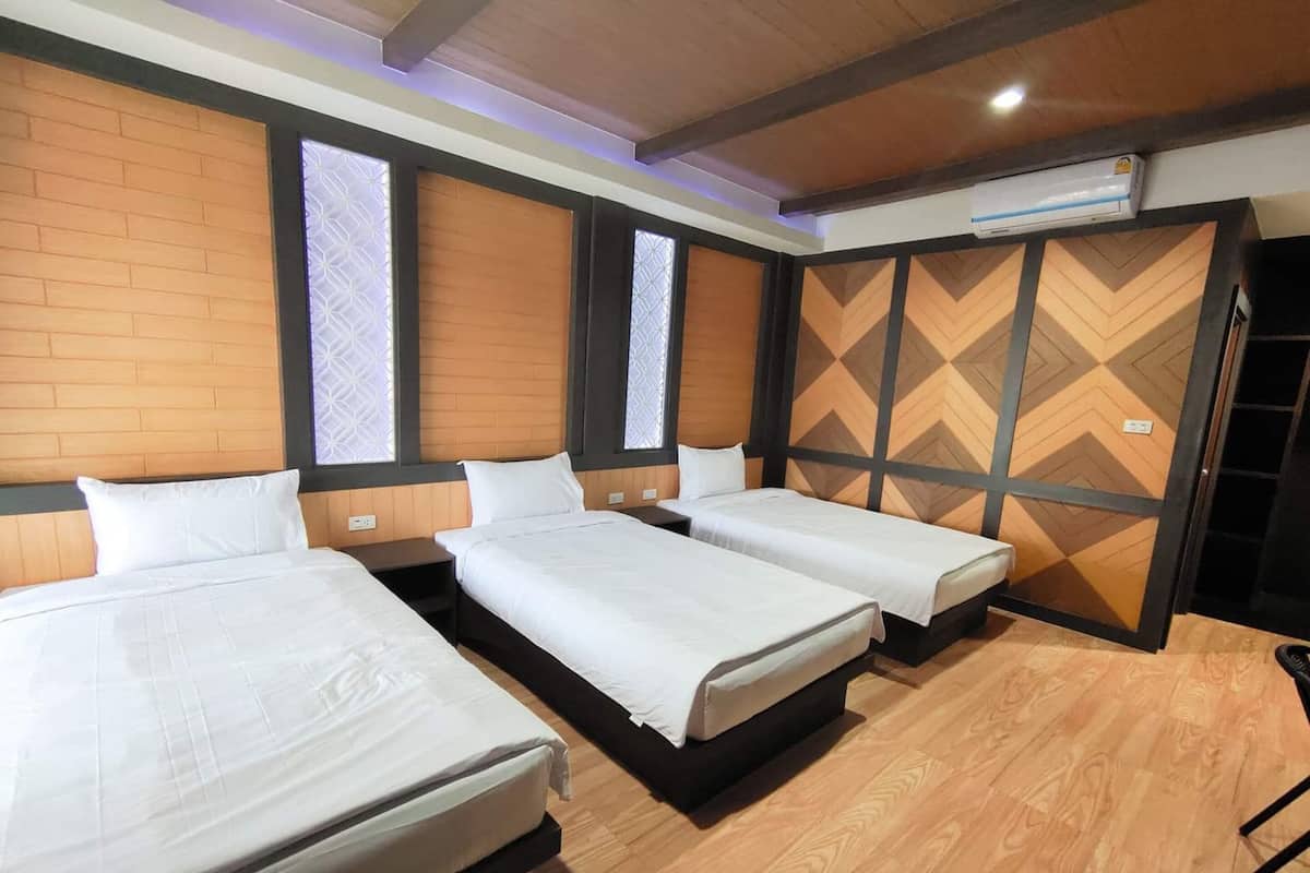 A hotel room with three single beds, wooden walls, and a herringbone-patterned partition.