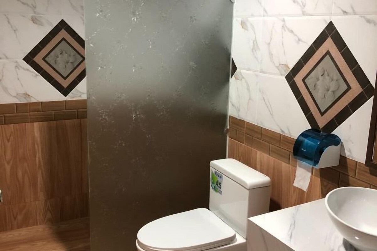 Un baño con inodoro, secamanos y lavamanos.