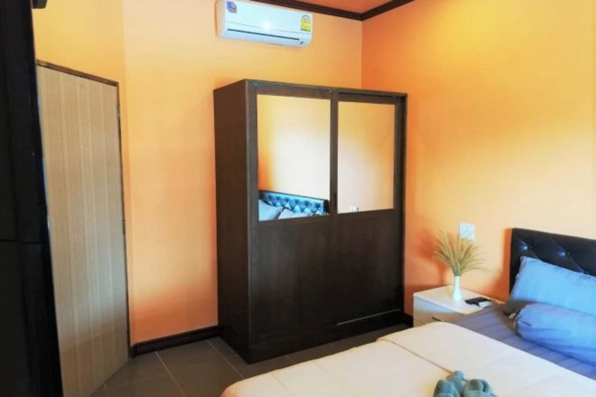 Una habitación de hotel con cama, mesita de noche, armario y aire acondicionado.