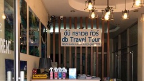 Un mostrador de recepción con un cartel de db Travel Tour, una silla y un cartel con información sobre excursiones.