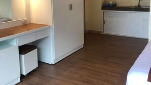 Un dormitorio con cama, escritorio, armario y kitchenette.