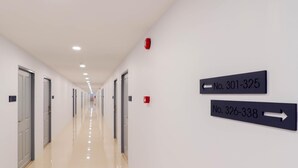 A long, well-lit hallway with doors numbered 302, 301-325, and 326-338. - Manonta Budget Hotel (Hat Yai)