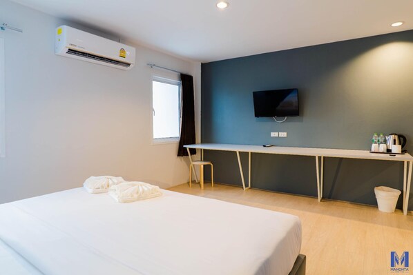Habitación de hotel con cama, escritorio, silla, aire acondicionado, televisor y ventana.