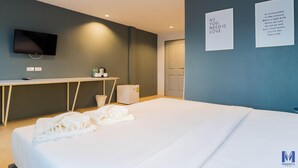 A modern hotel room with a bed, a desk, a television, and motivational wall art. - Manonta Budget Hotel (Hat Yai)