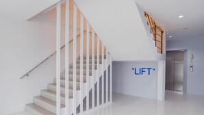 A modern interior with a staircase, a wall-mounted elevator, and a sign that reads "LIFT". - Manonta Budget Hotel (Hat Yai)