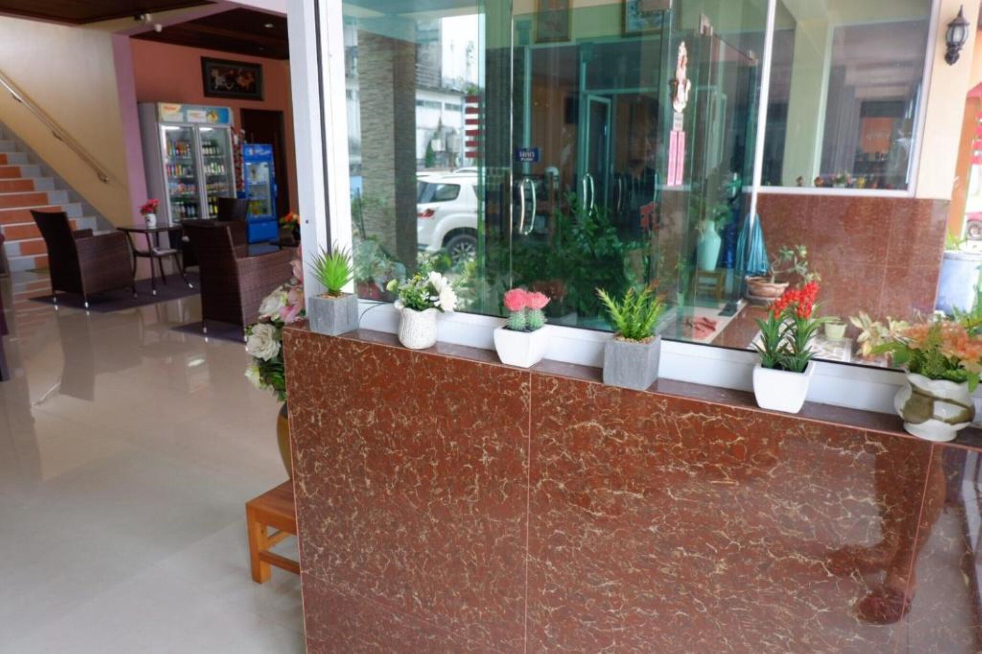 A reception area with a marble counter, potted plants, and a staircase in the background.