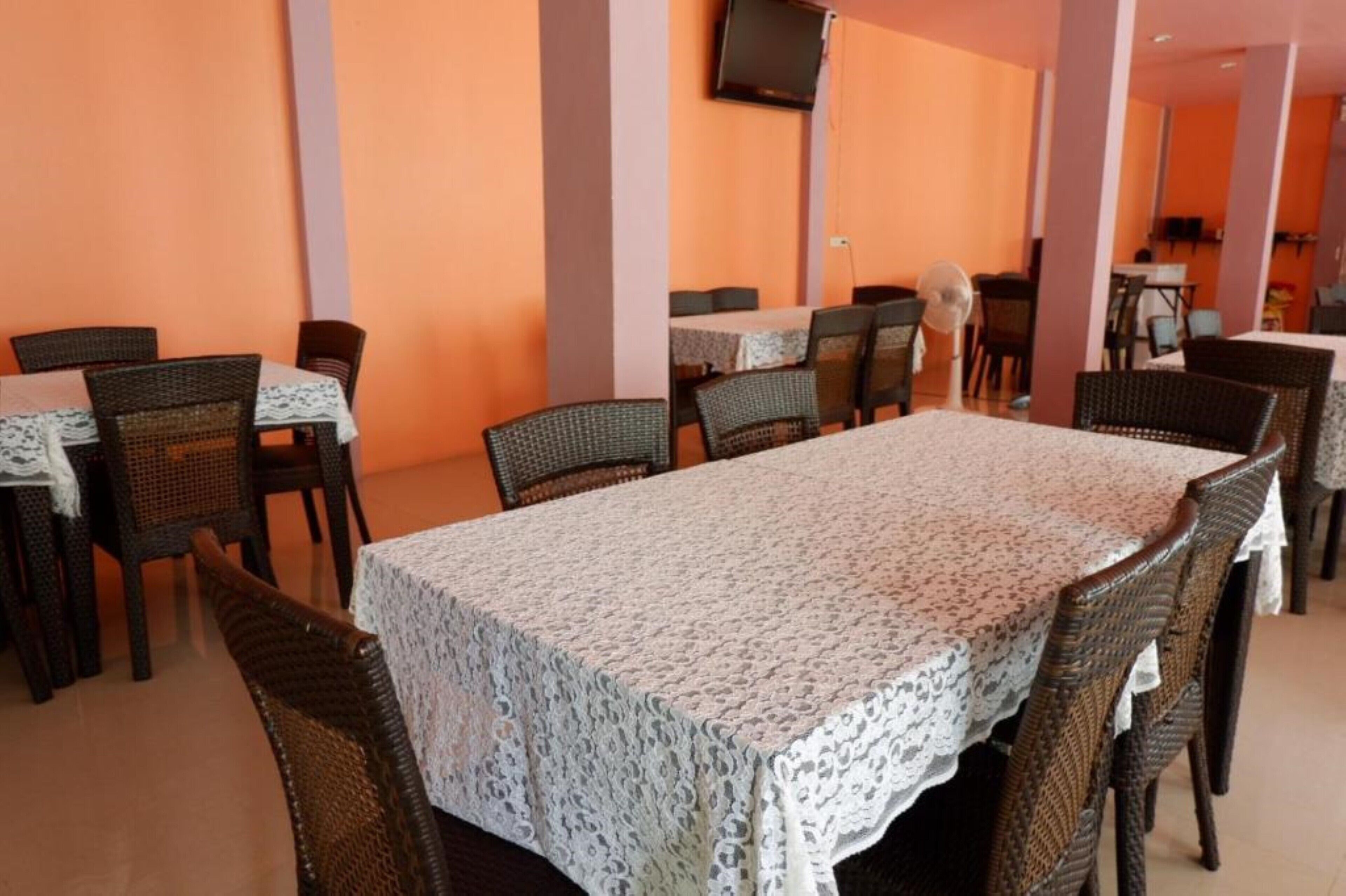 Un comedor con sillas y mesas de mimbre cubiertas con manteles de encaje.