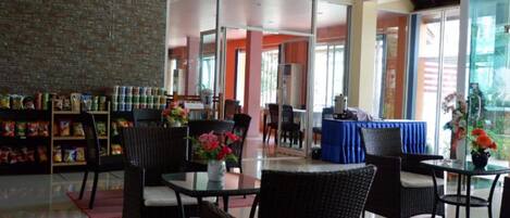A hotel lobby with wicker furniture, a brick wall, and a snack bar with various food items.