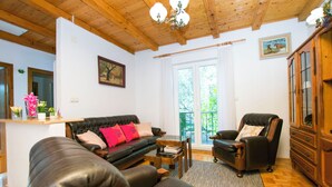 Una sala de estar con techo de madera, un sofá de cuero negro, una mesa de centro de madera y un sillón de cuero negro.