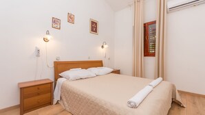Quarto com cama de madeira, mesa de cabeceira, luminária na parede e janela com cortinas.