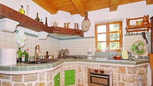 Una cocina con una isla de piedra, vigas de madera, un ventanal y varios electrodomésticos.