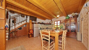 Una cocina amplia con armarios de madera, una mesa de comedor y una escalera que sube a un nivel superior.