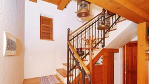 Una escalera de madera con barandilla de metal, una puerta de madera y un suelo de baldosas.