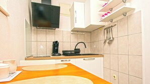 A modern kitchen with a wooden countertop, a black kettle, and white cabinets. - Apartment Bilberry (Biograd)