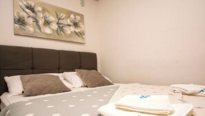 A neatly made bed with a polka dot bedspread, two pillows, and a folded towel on the side. - Apartment Bilberry (Biograd)