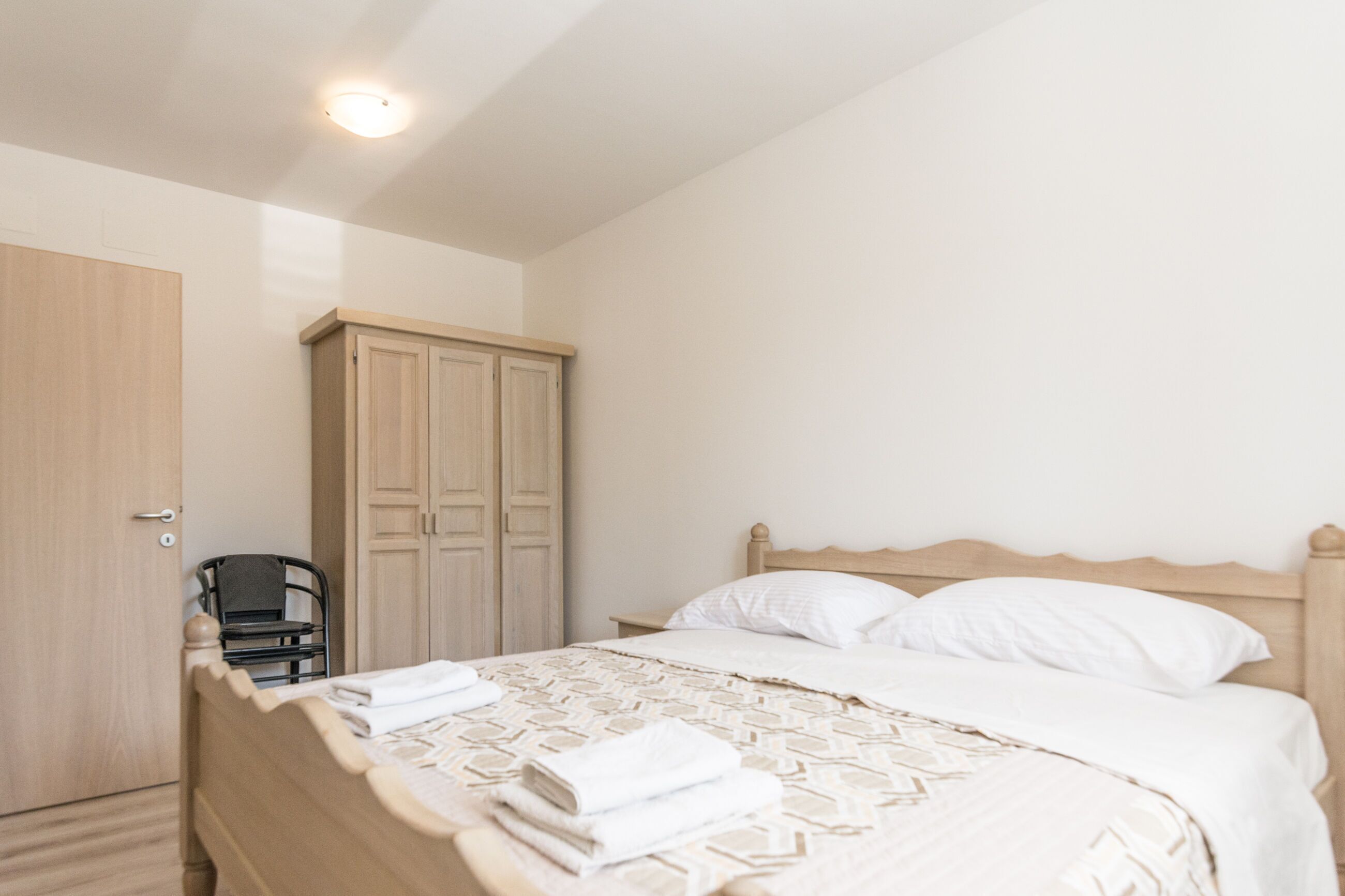 Ein Schlafzimmer mit einem Bett, einem Kleiderschrank und einem Sessel.