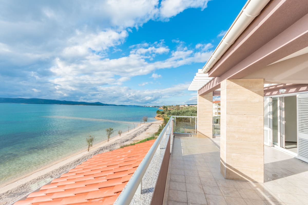 A balcony with a view of a beach and sea.
