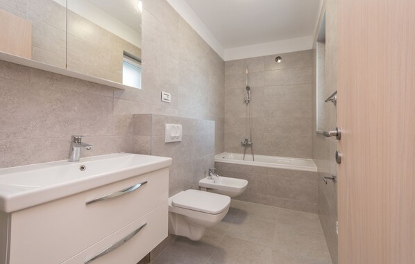 A modern bathroom with a sink, toilet, bidet, and bathtub. - Apartments Villa Marija II (Biograd)