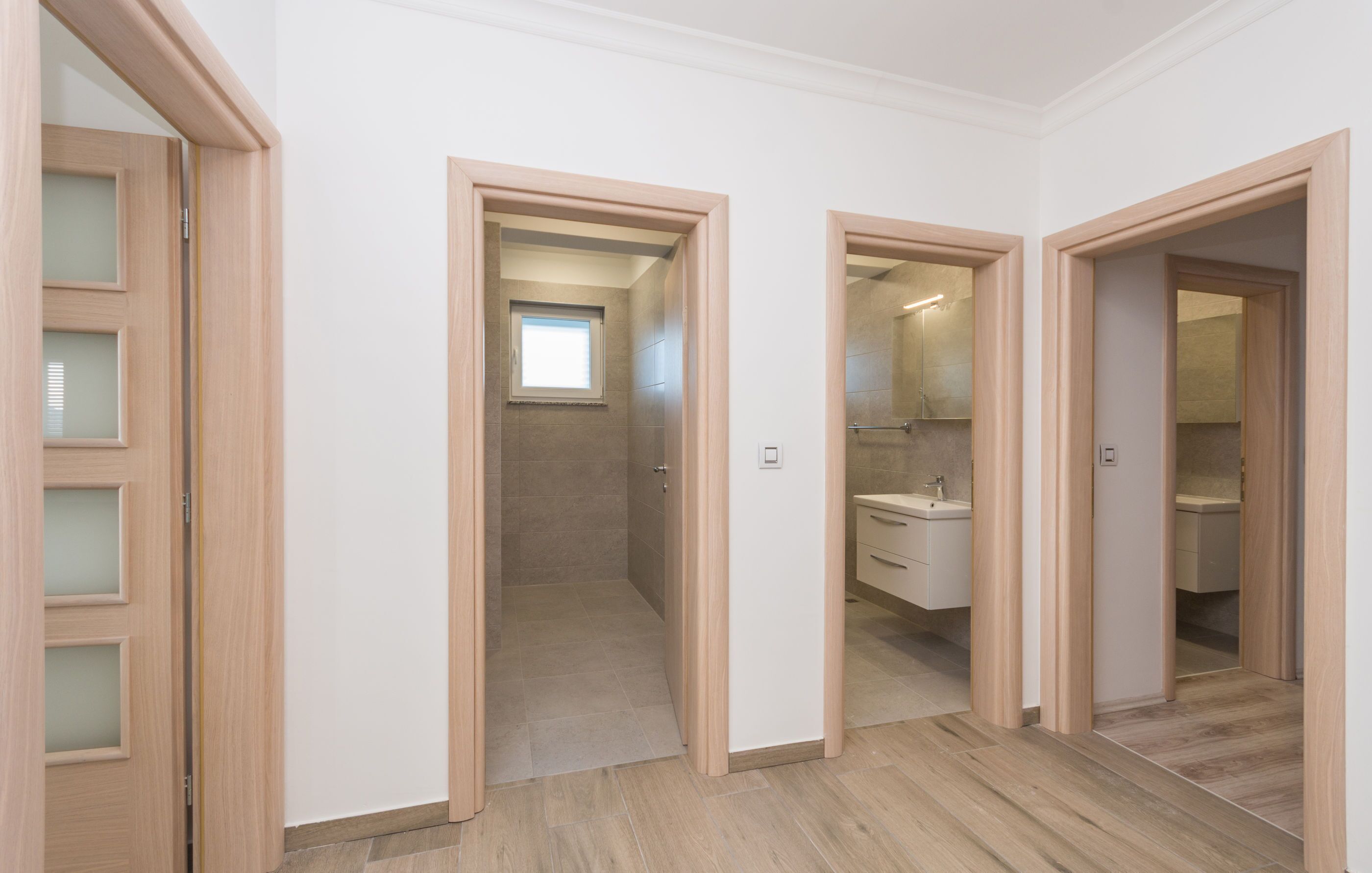 A hotel room with a wooden floor, a bathroom with a sink and mirror, and a shower.
