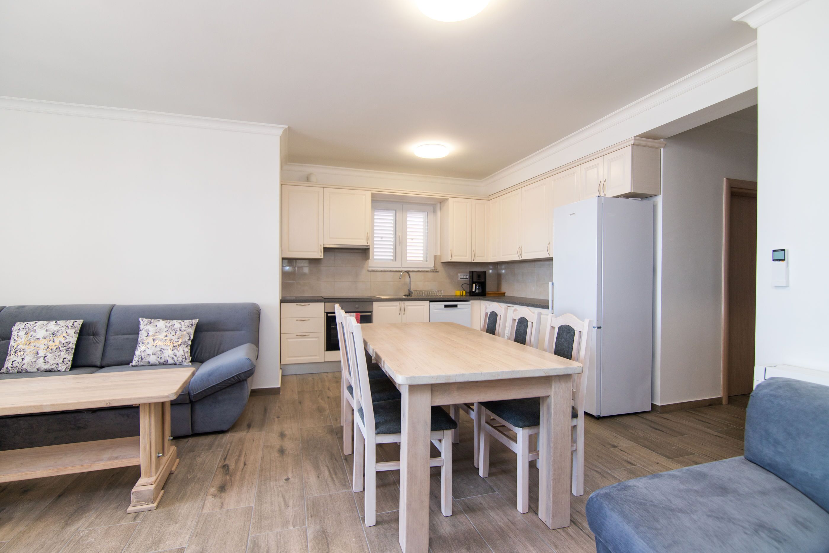 Una cocina compacta con una mesa y sillas, horno empotrado y refrigerador.