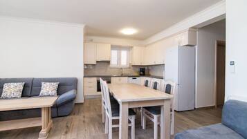 Una cocina compacta con una mesa y sillas, horno empotrado y refrigerador.