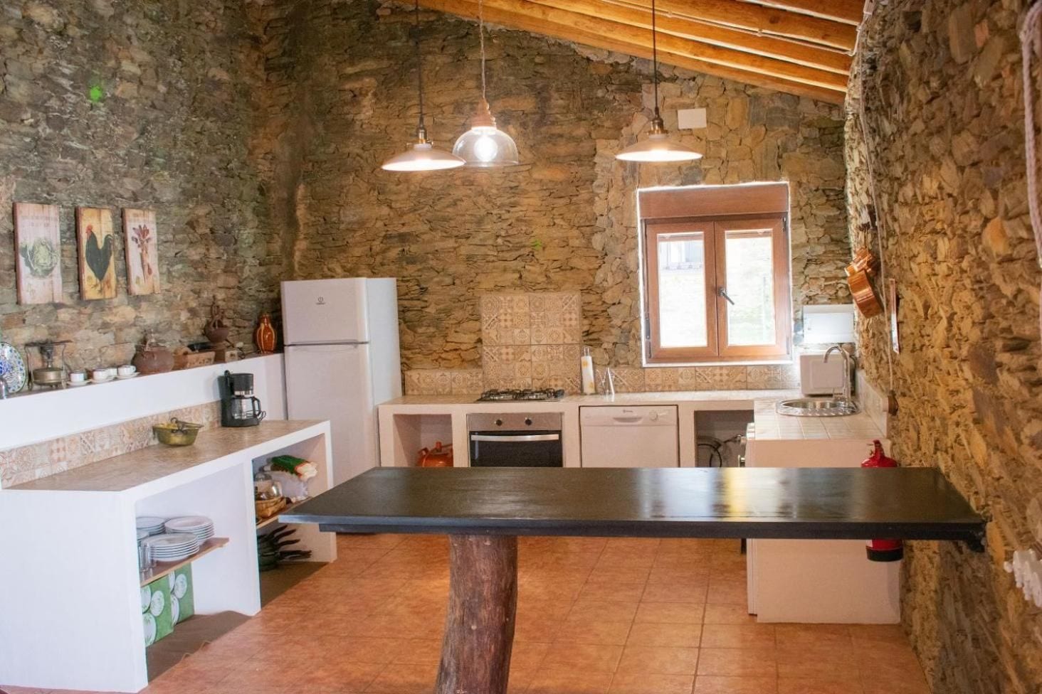 Una cocina rústica con paredes de piedra, techo de madera y una isla central.