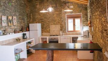 Una cocina rústica con paredes de piedra, techo de madera y una isla central.