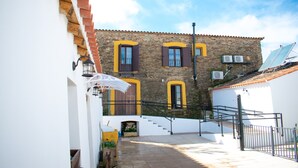 A narrow alleyway leading to a building with a stone facade, a small staircase, and a white wall with a door. - La Casa Grande de Adolfo (La Codosera)