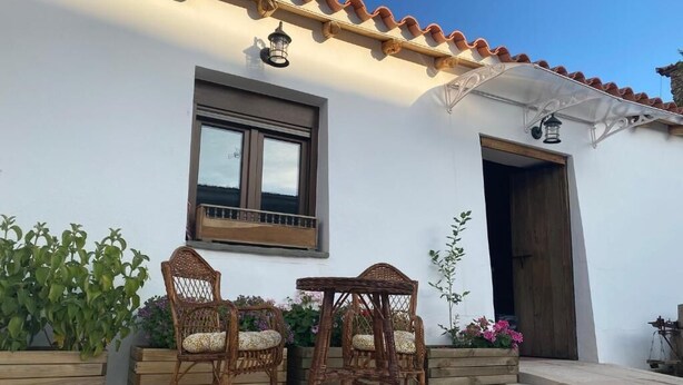 A patio with wicker chairs and a table, a window, and a door. - La Casa Grande de Adolfo (La Codosera)